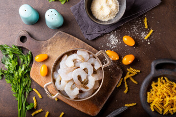  Raw shrimps in a pan and ingredients for making shrimp pasta on the dark background top view