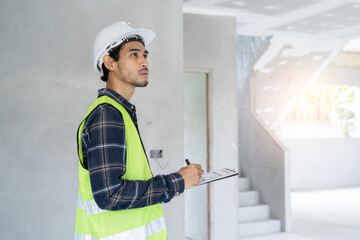 Asian inspector checking structure of new property and taking note in the clipboard for review and...