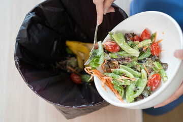 The housewife is throwing the leftover food from the meal into the bin