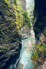 High-angle view of forest and river flowing through Taroko National Park, Taiwan. Clear blue water streams over rocks with moss in the crevices of the mountain. Idea for a nature background.