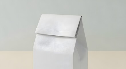 A minimalist view of a closed white paper bag sitting on a light surface against a plain background