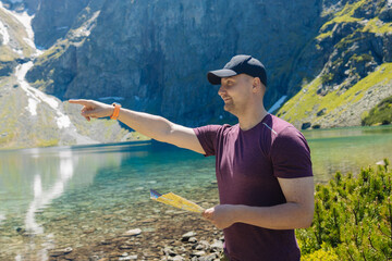 Beautiful panoramic view of a clear alpine lake surrounded by green forest and rugged mountain peaks under a bright blue sky. A peaceful summer day in nature, perfect for hiking, relaxation, and