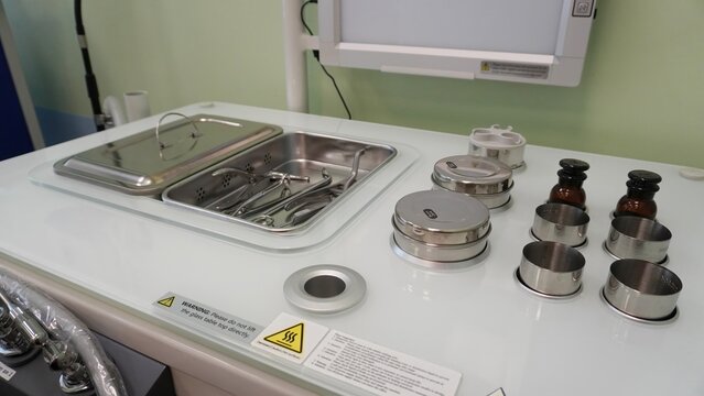 A medical table with ENT instruments, sterile containers and glass vials. The metal tray contains tweezers, clamps and spatulas. Equipment for carrying out procedures in the otolaryngologist's office.