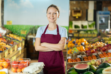 Positive and friendly store woman employee stands with arms crossed on chest and waits for...