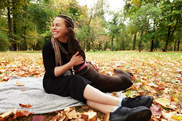 Woman enjoying a joyful moment with her dog in an autumn park