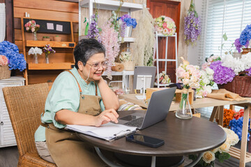 Senior woman, florist small business owner, digital skill, manages inventory on laptop, confident with technology in retail operations, bookkeeping tasks, remote access to financial control and supply