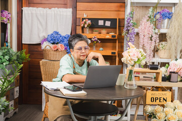 Asian senior woman, florist, small business owner waiting, looking at laptop for online order, open flower shop with no walk-in customers, aging entrepreneur journey,  using laptop technology