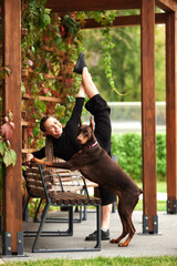 Woman practicing yoga outdoors with a Doberman in a park setting