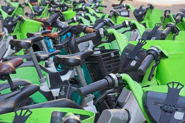 Close up of many green electrical rental bikes parked and ready to be used in a bike sharing...