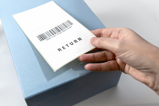 A woman's hand holds a return label over the blue box