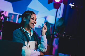 Charming female influencer hosting a live podcast with vibrant neon lighting in a modern studio...