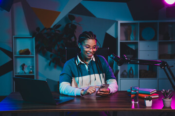 Podcaster woman creating content in a home studio with neon lighting and modern equipment for...