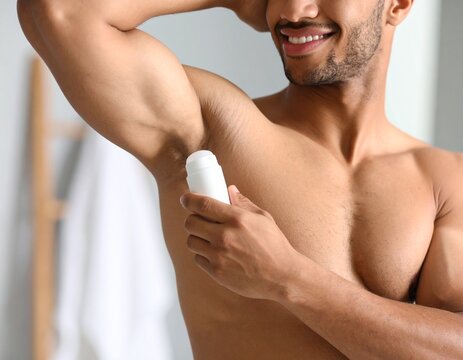 African American man applying deodorant to armpit, conveying daily hygiene routine and freshness.