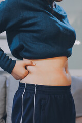 woman's hand holding excessive belly fat, overweight concept