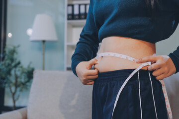 woman's hand holding excessive belly fat, overweight concept