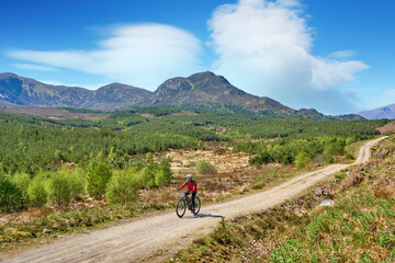 nice senior woman riding her electric mountain bike  in the highlands of Glen Affric Nature reserve, Scotland, UK