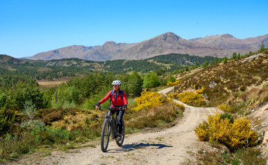 nice senior woman riding her electric mountain bike  in the highlands of Glen Affric Nature...