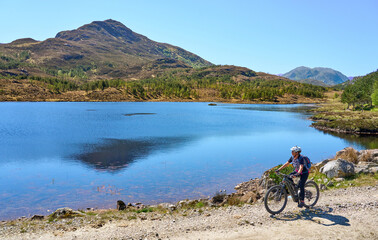 nice senior woman riding her electric mountain bike  in the highlands of Glen Affric Nature...