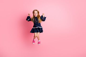 Energetic young girl in casual dress posing happily against a vibrant pink background, showcasing lively childhood joy and style
