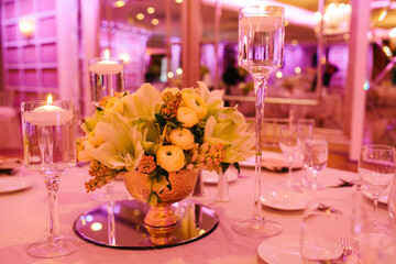 Elegant floral centerpiece with candles at a festive indoor event during evening hours