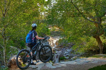 nice senior woman riding her electric mountain bike at the wild river Dee in the Cairn Gorms...