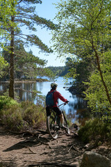 nice senior woman riding her electric mountain bike at Loch An Eilein in the Cairn Gorms National Park near Aviemore Scotland, UK