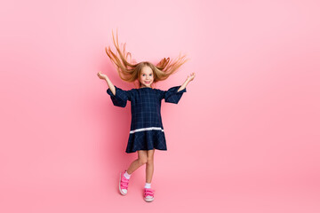 Happy young girl in a stylish dress showcasing her charm and beauty on a vibrant pink background with lively hair