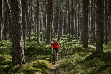 nice senior woman riding her electric mountain bike in the fir forest at Loch An Eilein in the Cairn Gorms National Park near Aviemore Scotland, UK