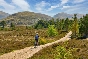 nice senior woman riding her electric mountain bike  in the highlands of Cairn Gorms National Park , Scotland, UK