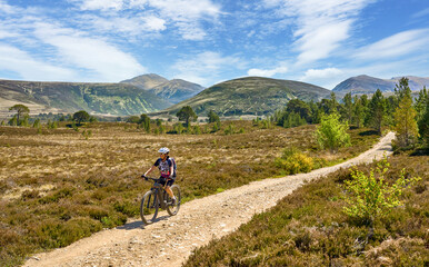 nice senior woman riding her electric mountain bike  in the highlands of Cairn Gorms National Park , Scotland, UK