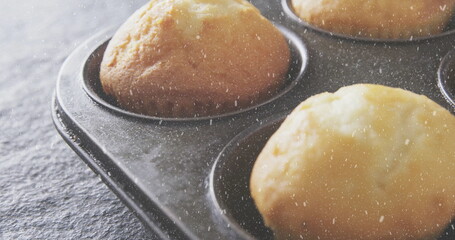 Displaying close-up metal muffin tin holding golden-brown muffins on dark kitchen countertop