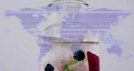 Showing clear glass bottle with ice, raspberries, blueberries and mint on studio countertop, glitch