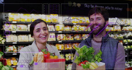 Smiling couple shopping in supermarket aisle, holding paper bags with fresh vegetables and baguette