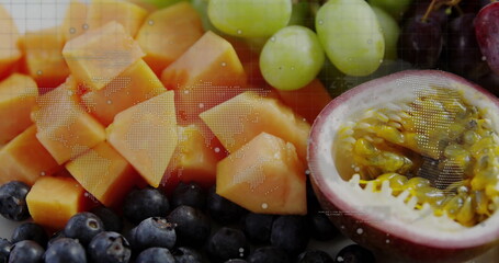 Displaying papaya cubes, grapes, blueberries, halved passion fruit on studio table with map overlay