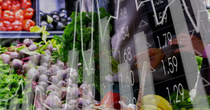 Couple holding kale and basket, checking prices on smartphone in supermarket with market graphs