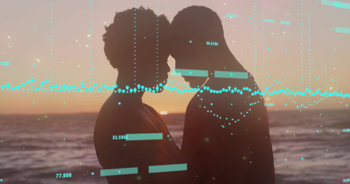 Standing silhouetted couple touching foreheads on sandy shoreline at sunset, with numeric readouts