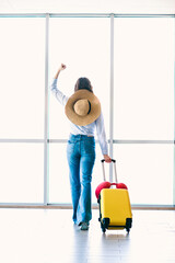Charming woman at airport with suitcase ready for travel, expressing excitement for upcoming...