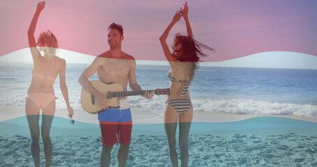 Friends in bikinis and trunks strumming acoustic guitar singing into mic dancing on beach at sunset