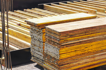 Stacked yellow formwork boards. Construction materials on building site. Industrial wood panels for...