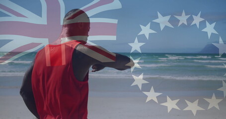 Man in red shirt checking smartwatch on beach, waves, Union Jack and white star circle overlays