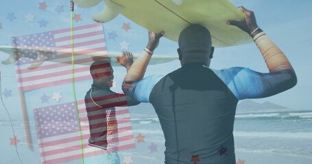 Walking father and son wearing wetsuits and carrying surfboards at sandy beach, with flag overlay
