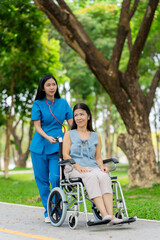 Caregiver takes elderly in wheelchair to walk in the park for health therapy, insurance concept for the elderly, happy retirement