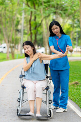 Caregiver takes elderly in wheelchair to walk in the park for health therapy, insurance concept for the elderly, happy retirement
