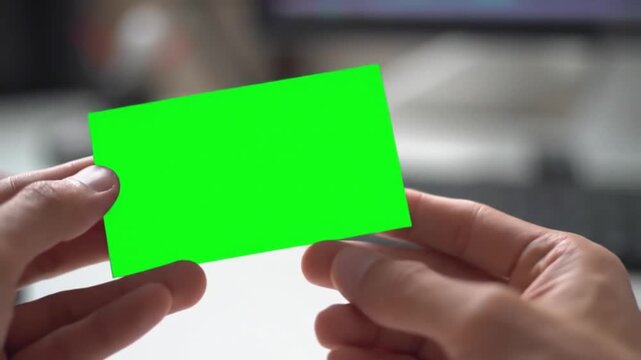 Close-up of a person's hands holding a green screen business card mockup