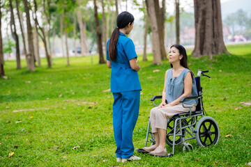 Caregiver takes elderly in wheelchair to walk in the park for health therapy, insurance concept for the elderly, happy retirement