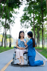 Caregiver takes elderly in wheelchair to walk in the park for health therapy, insurance concept for the elderly, happy retirement
