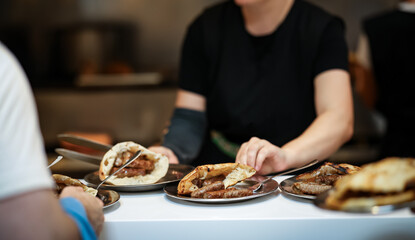 Serving traditional grilled sausages in flatbread at a local Balkan eatery, with warm lighting and...