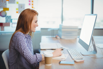 Wireless keyboard and mouse resting on wooden desk near window beside open notebook and coffee cup