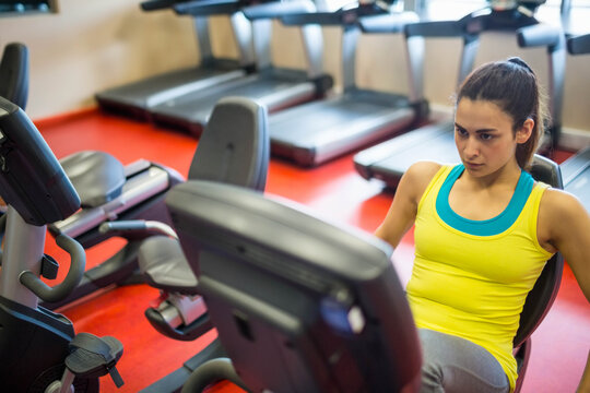 Fototapeta Recumbent exercise bike resting on red gym floor with treadmills lining window wall in bright light