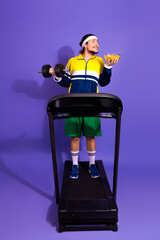 Young man exercising on a treadmill holding a weight and a bowl of chips in a fun retro-themed...